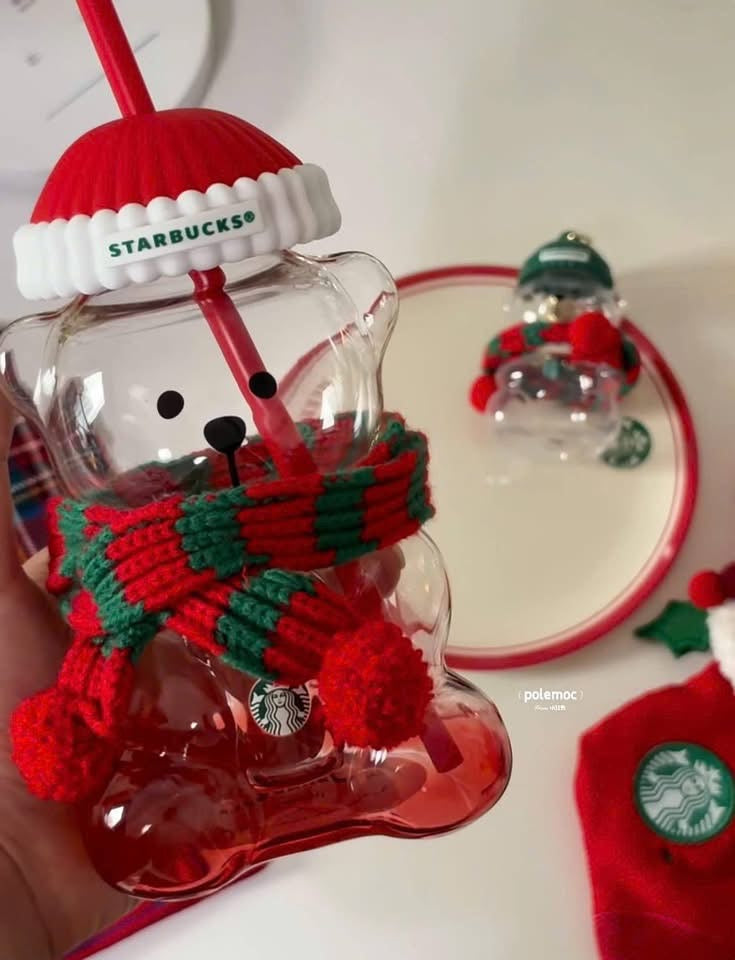 Detalle del vaso de vidrio Starbucks China Christmas 2026 con forma de osito, gorro rojo y bufanda navideña.